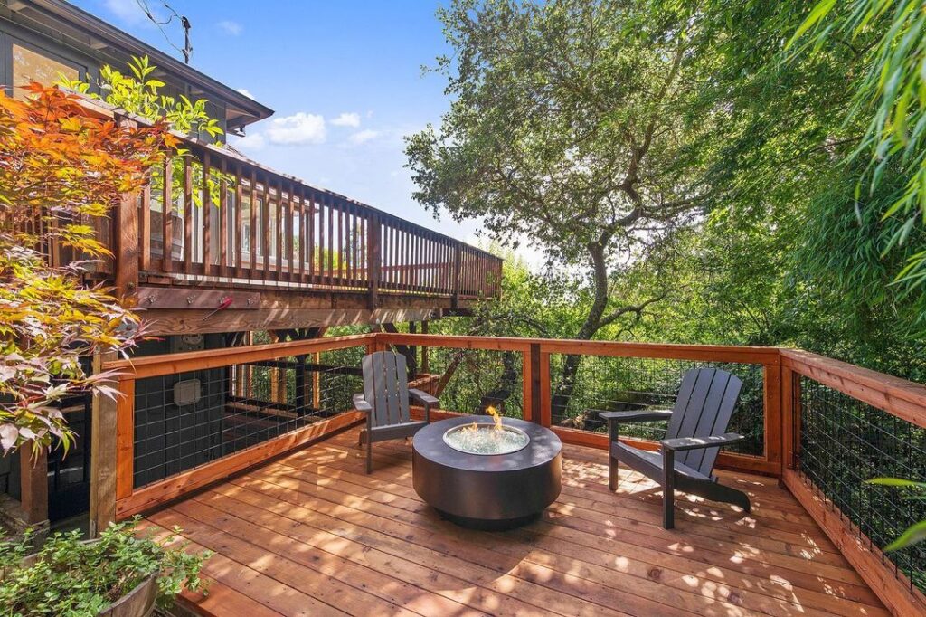 This deck has dark brown Adirondack chairs and a circular fire pit.